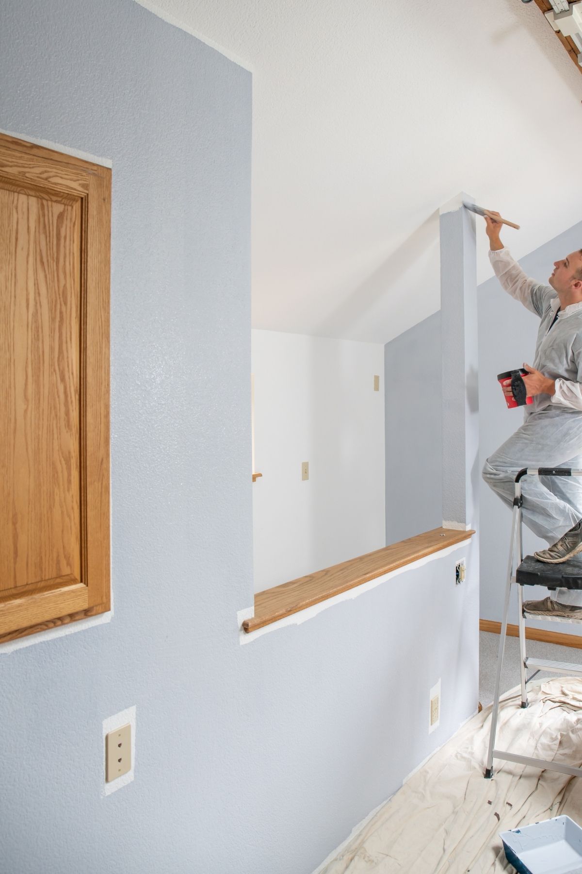 Peintre professionnel utilisant un rouleau pour peindre un mur intérieur à Joliette